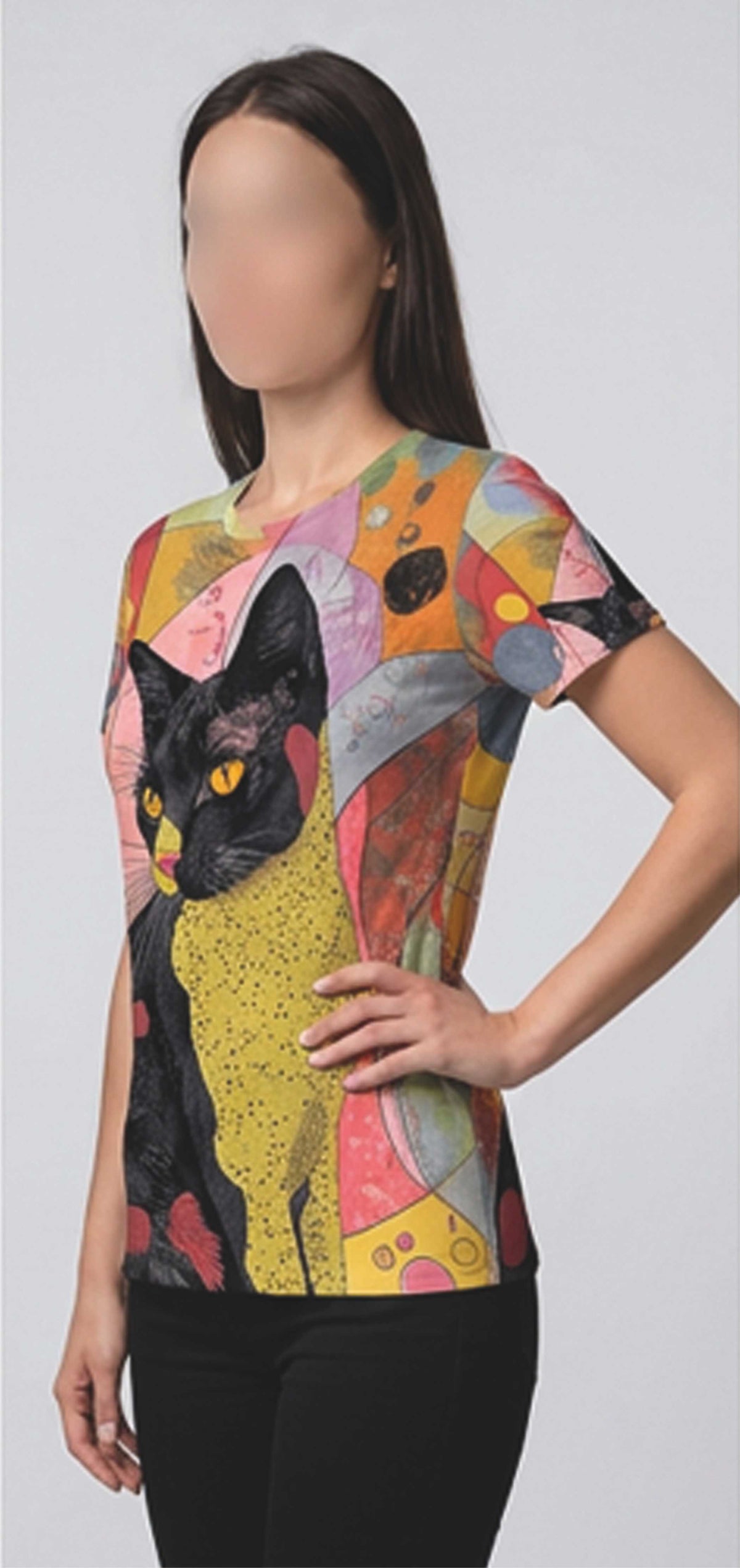 A woman wearing a short-sleeve crewneck t-shirt with a colorful abstract art print featuring a black cat with yellow eyes on a light gray background.