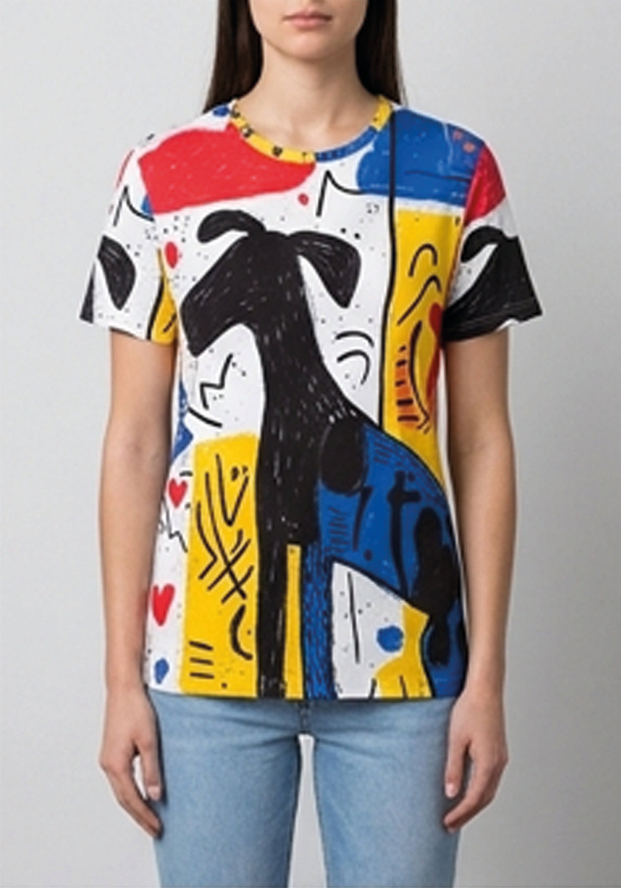 A woman wearing a short-sleeve crewneck t-shirt with a vibrant abstract art print in red, yellow, blue, black, and white, paired with light blue jeans, against a plain light gray background.