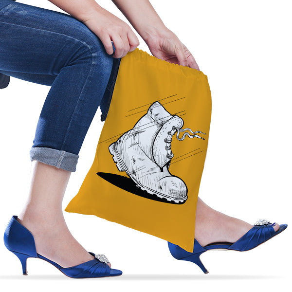 Person holding a yellow drawstring bag with a shoe design, wearing blue jeans and high heels.